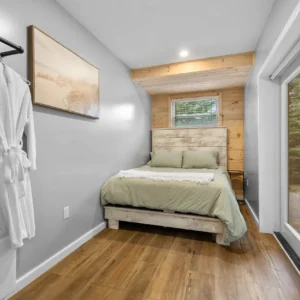 Bedroom with a bed, pillows, a frame on the wall, a hanger with a robe, a switchboard, a ceiling