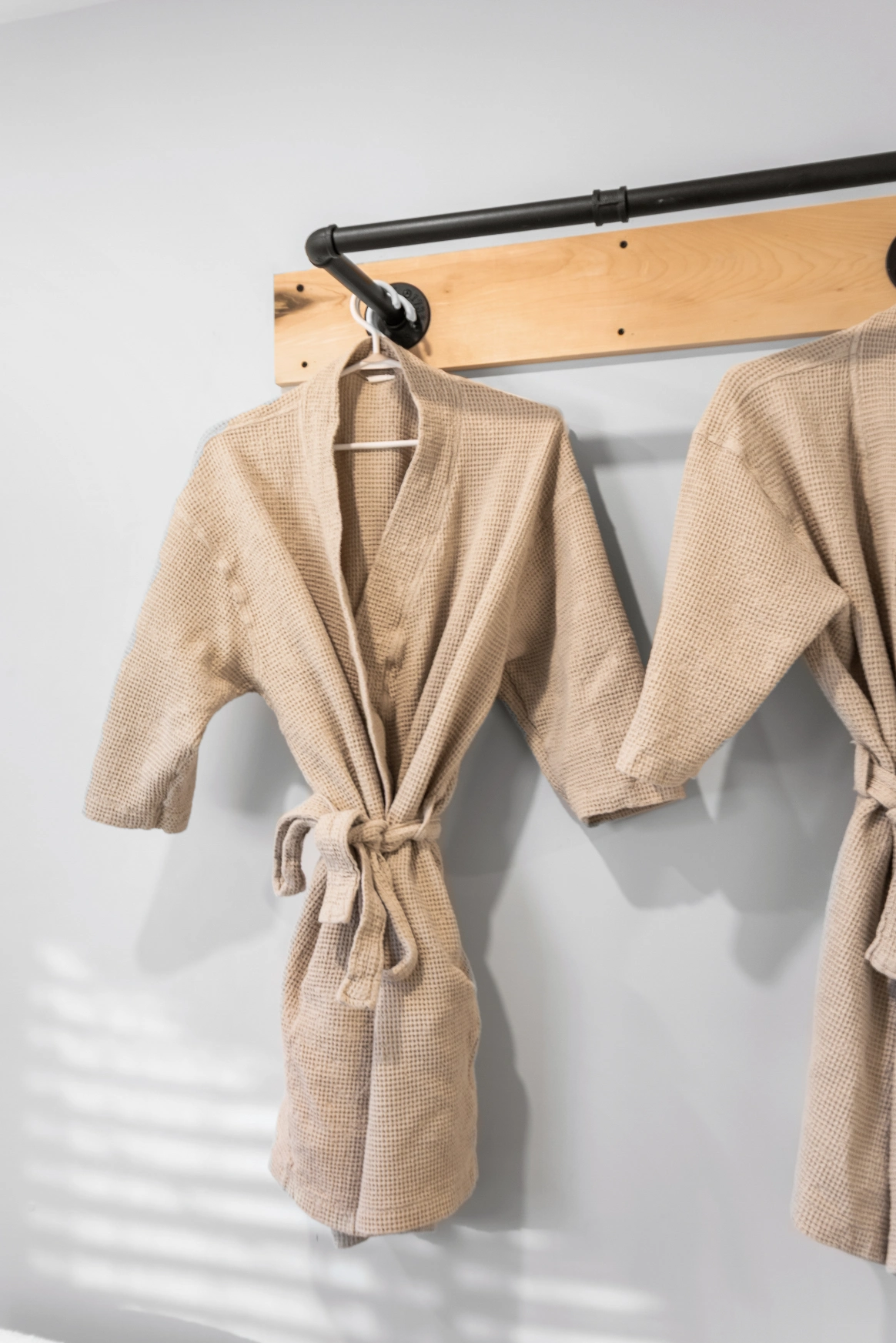 Beige bathrobes on industrial pipe rack