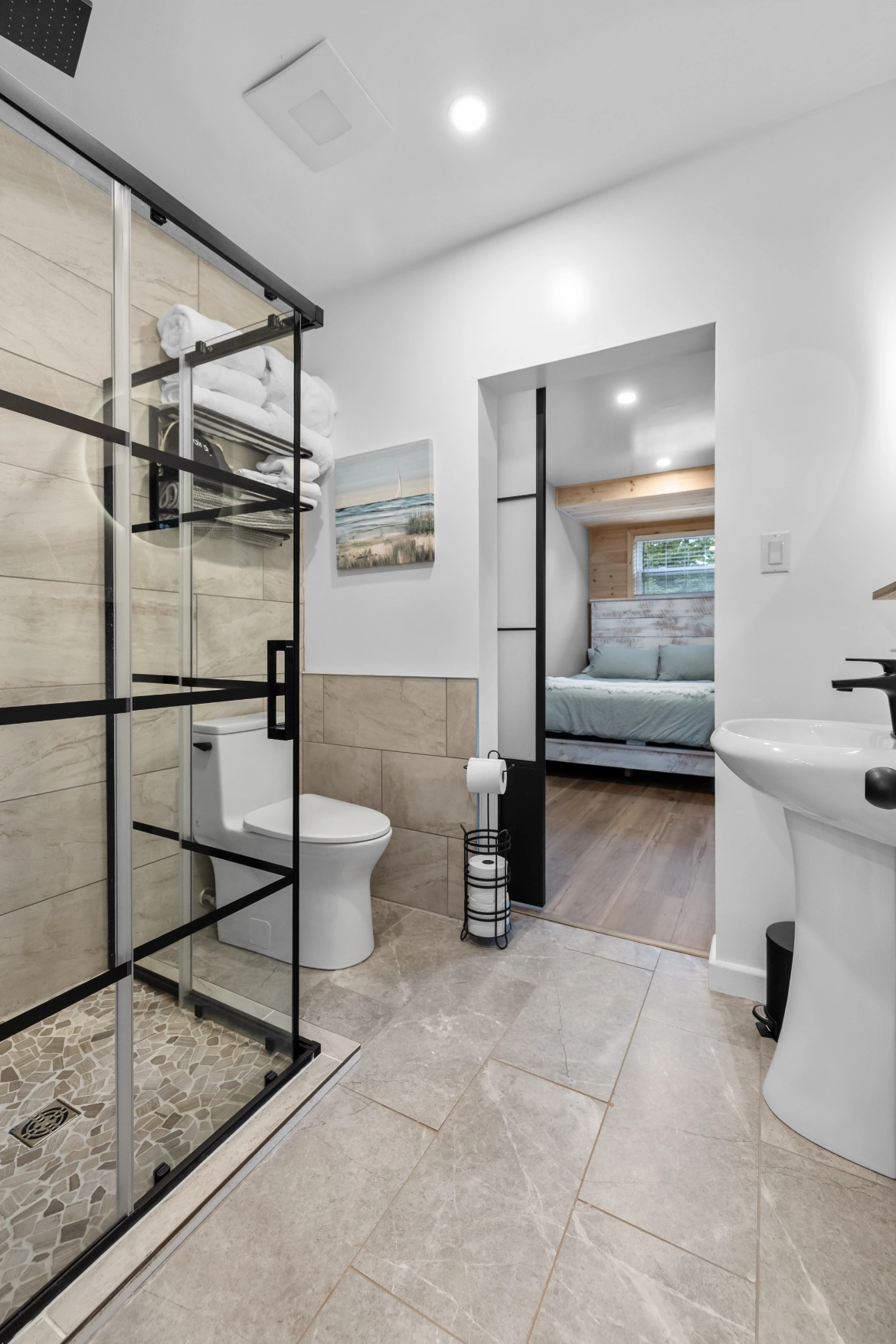 Stylish tiled bathroom with glass shower and pedestal sink
