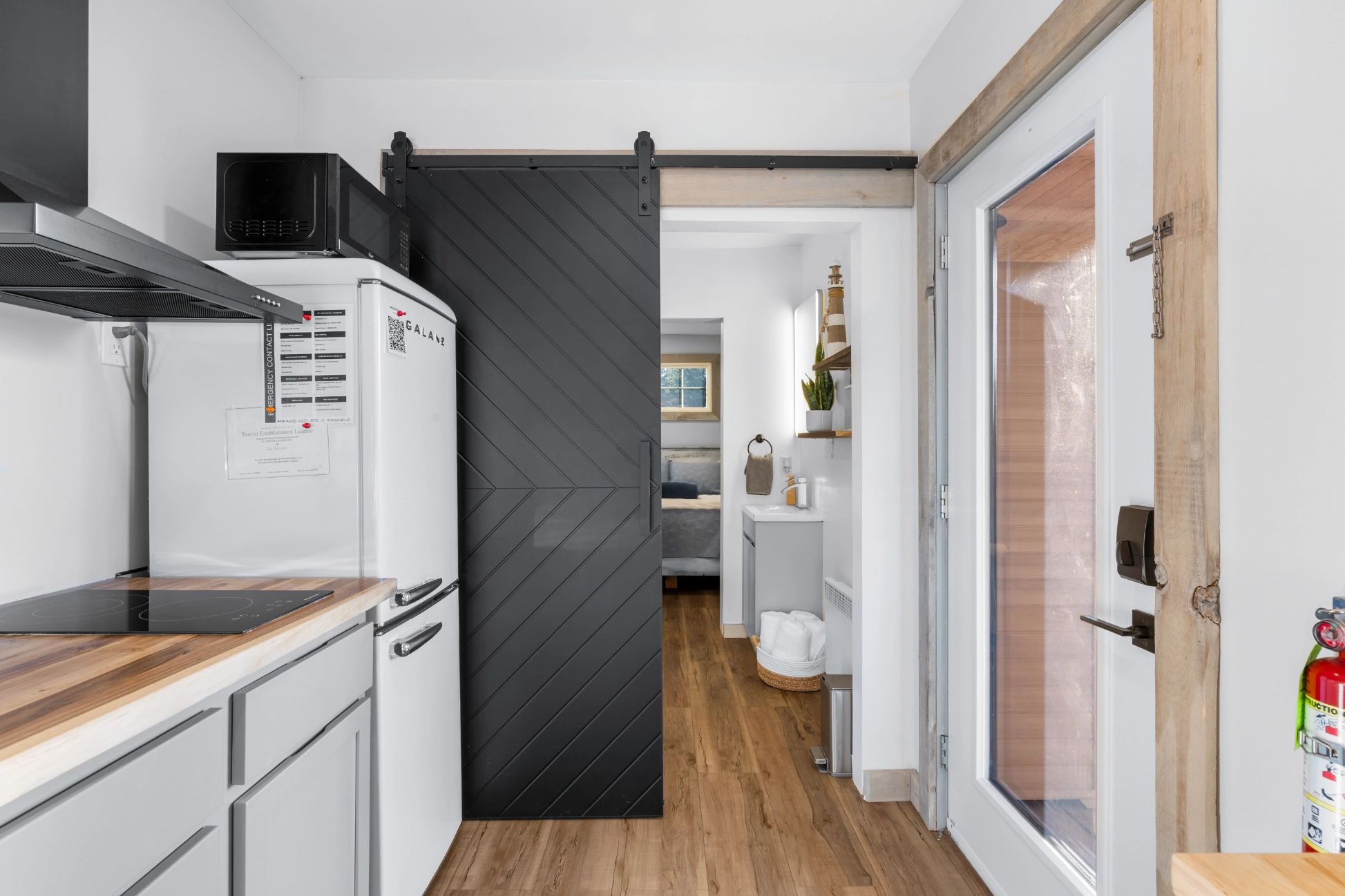 Compact kitchen, barn door to bedroom, white walls